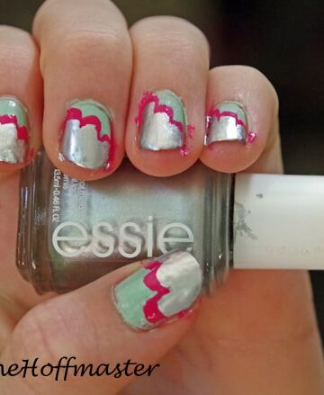 closeup of child's hand holding nail polish and with a simple nail art design on the fingernails.