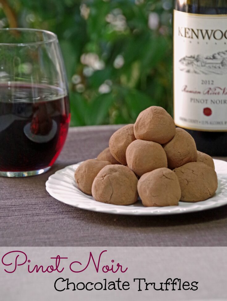 chocolate pinot noir truffles on a white plate with a bottle of red wine