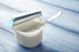 Plastic cup with yummy yogurt on wooden background