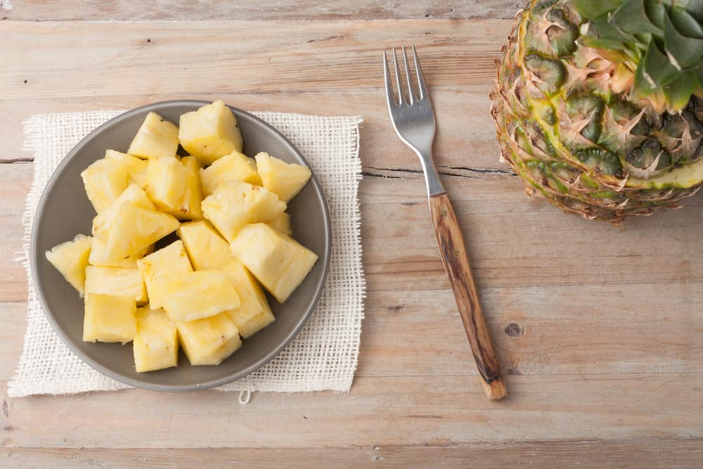 pineapple chunks on a plate on wooden rustic background