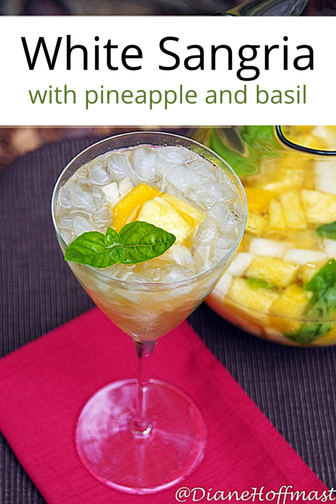 White Sangria with pineapple and basil in a pitcher and long stemmed glass