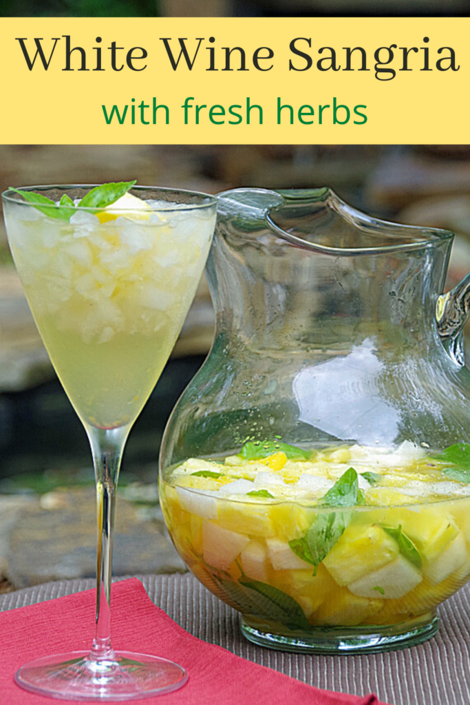 white wine sangria in pitcher next to glass with homemade sangria in it