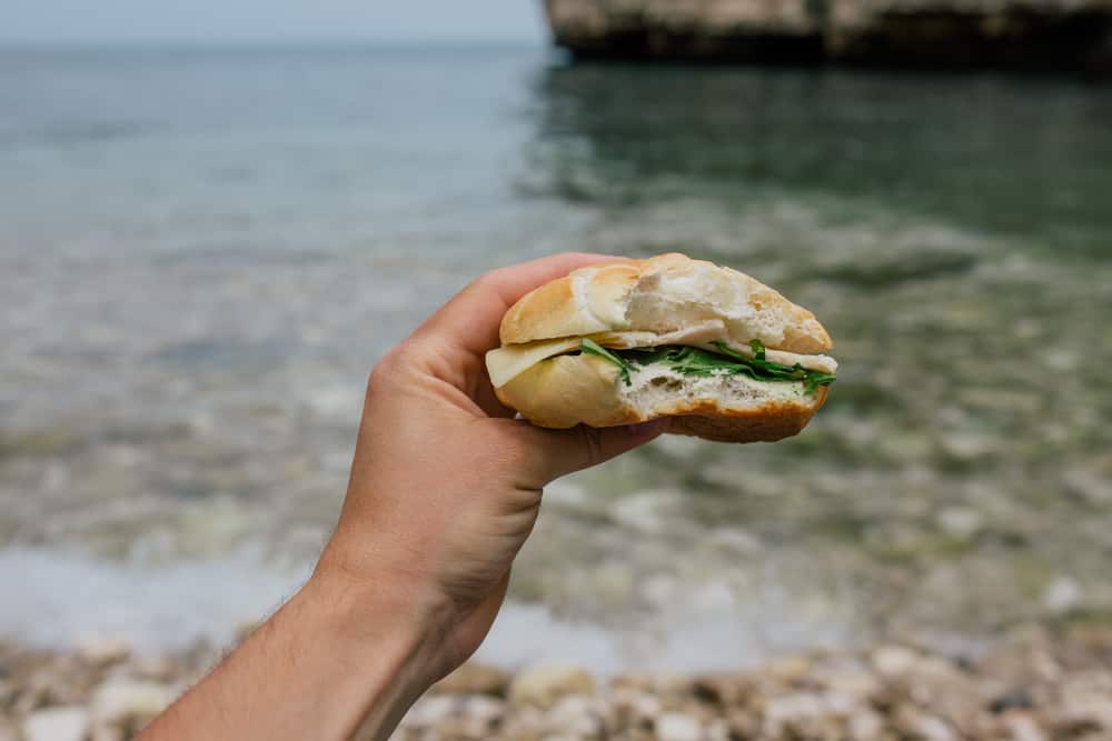 Sandwich in a hand in front of a river