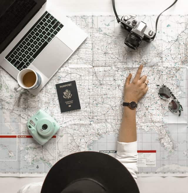 woman planning adventure with computer and camera and map