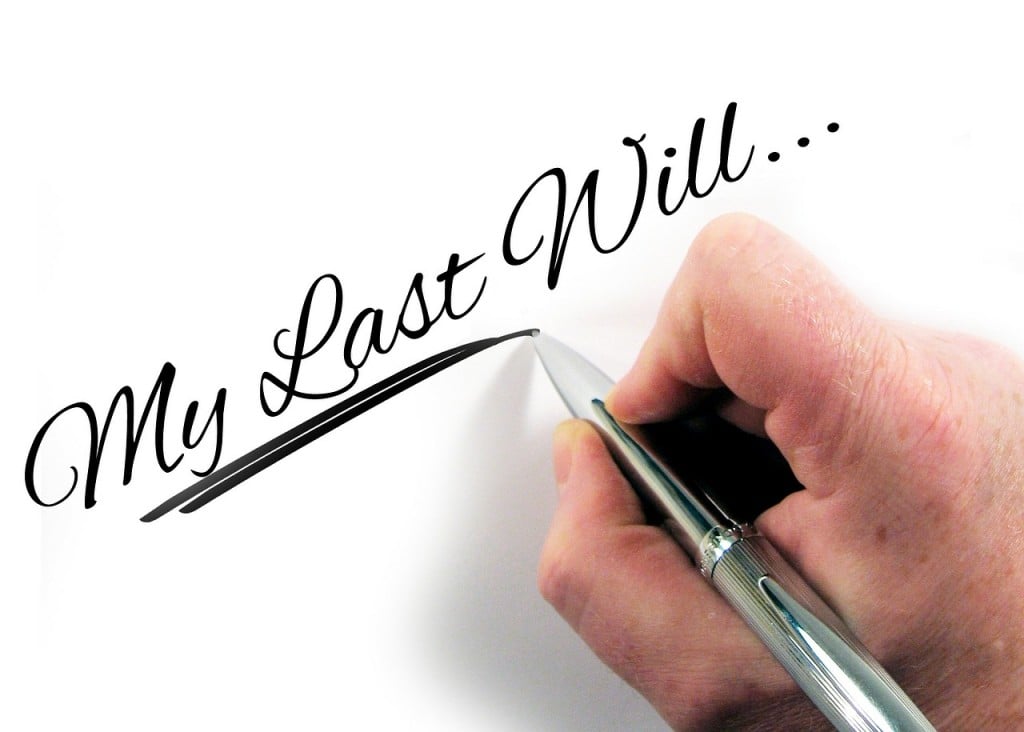 persons hand holding pen with text overlay 'my last will'