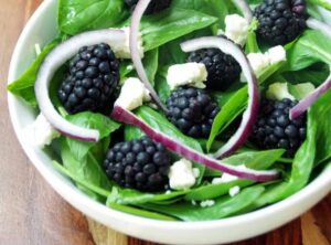 spinach and basil salad with onions and feta in a white bowl
