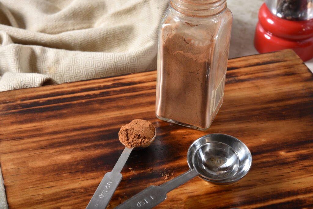 A teaspoon full of ground cinnamon spice on a cutting board