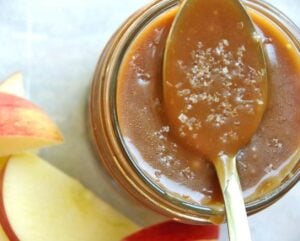 salted caramel sauce in mason jar with spoon and apples