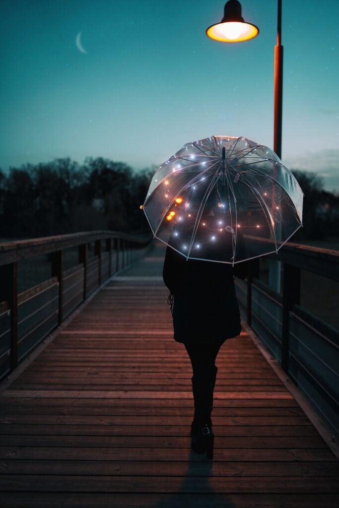 woman walking alone at night with umbrella