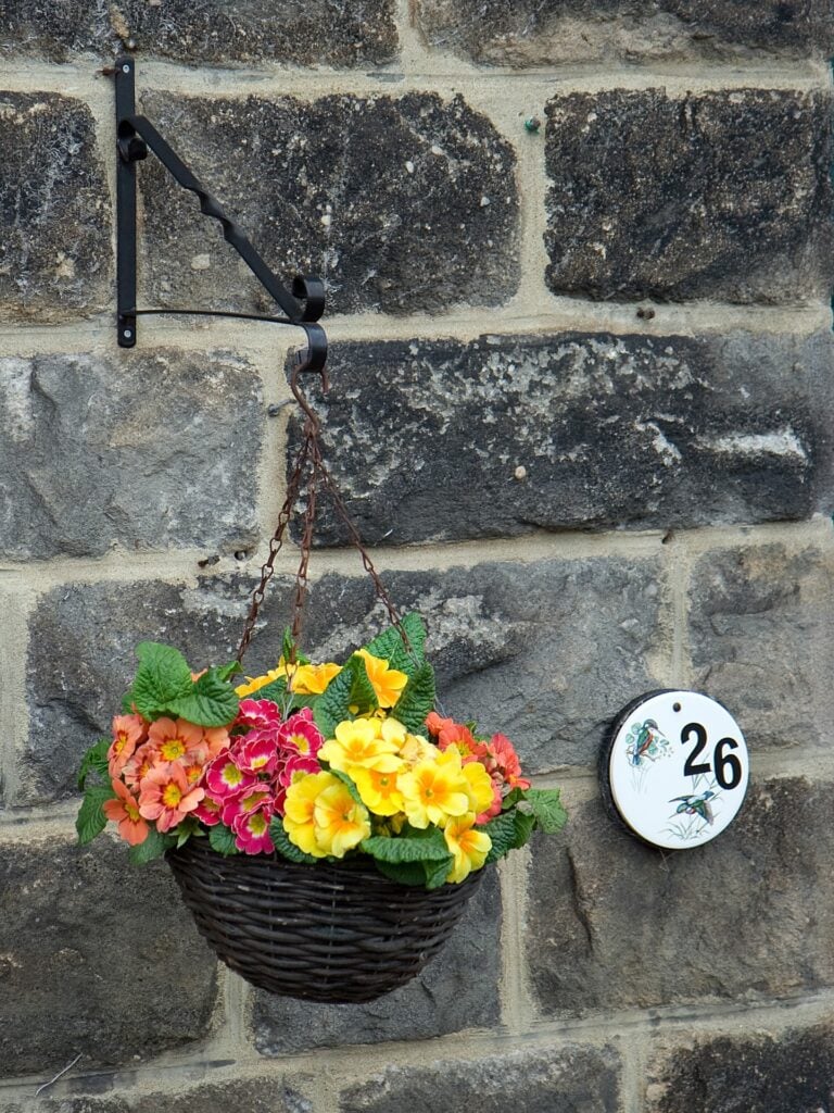 house numbers and flowers on a rock wall