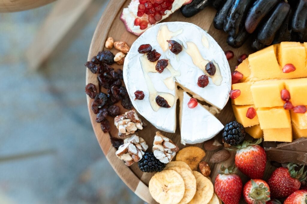 cheese and fruit on a cutting board to serve with wine