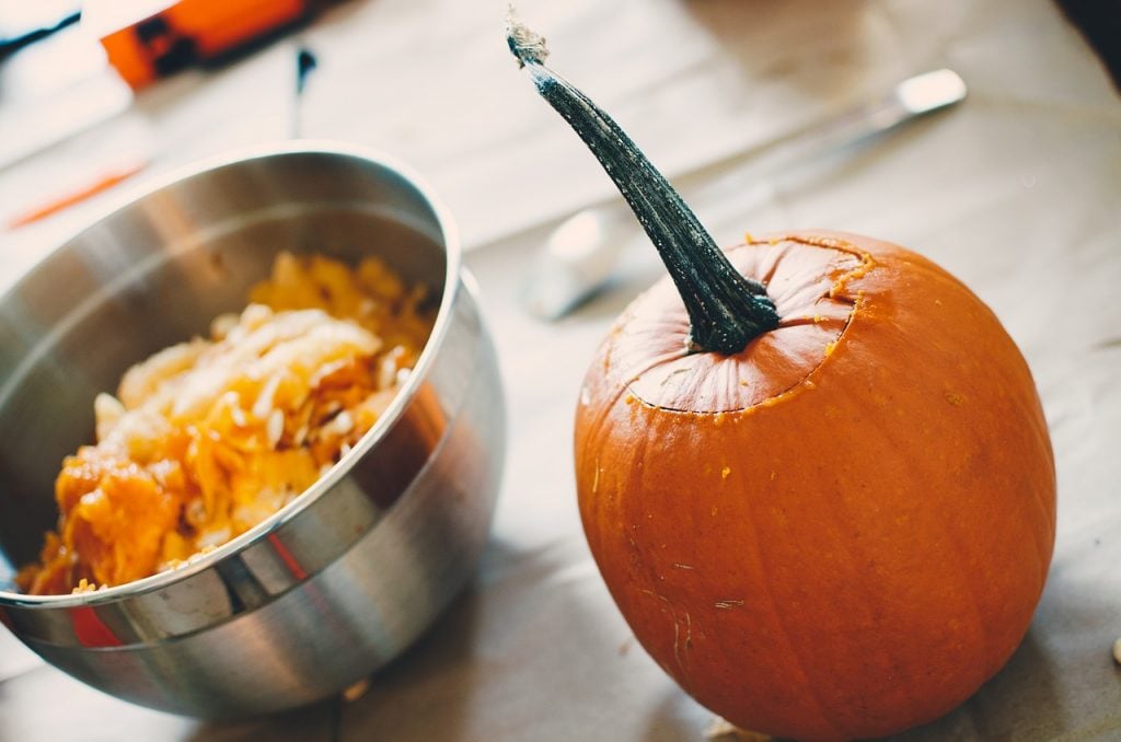 pumpkin and bowl of seeds on a kitchen counter