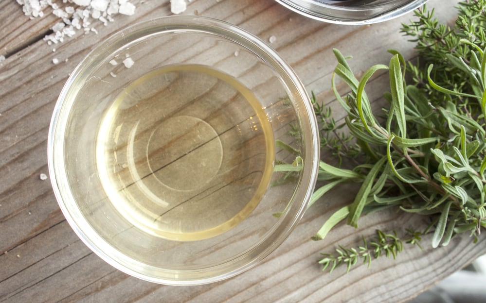 White wine vinegar, near thyme and rock salt. On wooden background