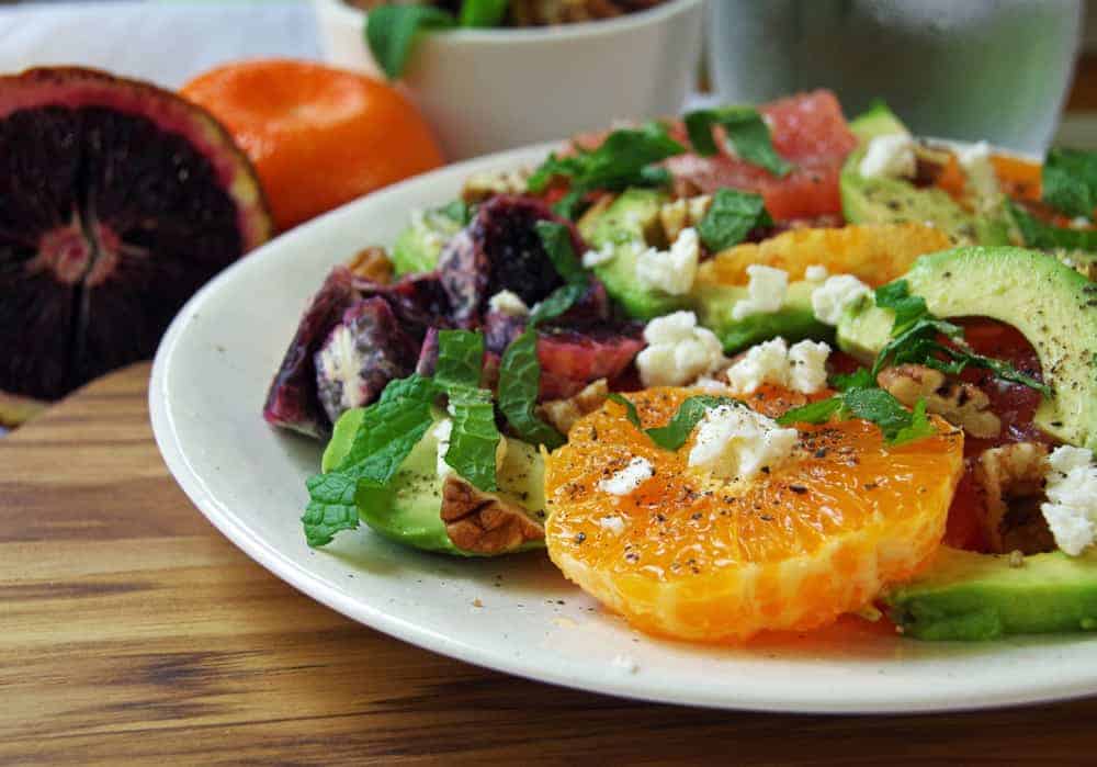 white plate with salad of oranges and avocado