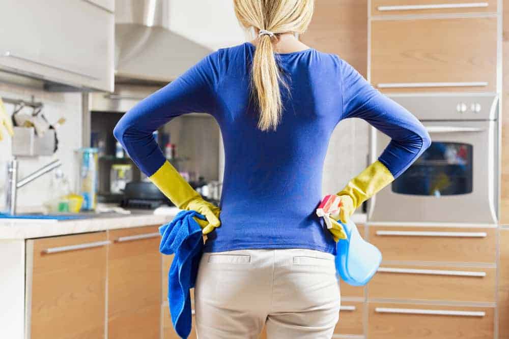 rear view of woman with yellow gloves in kitchen doing housework