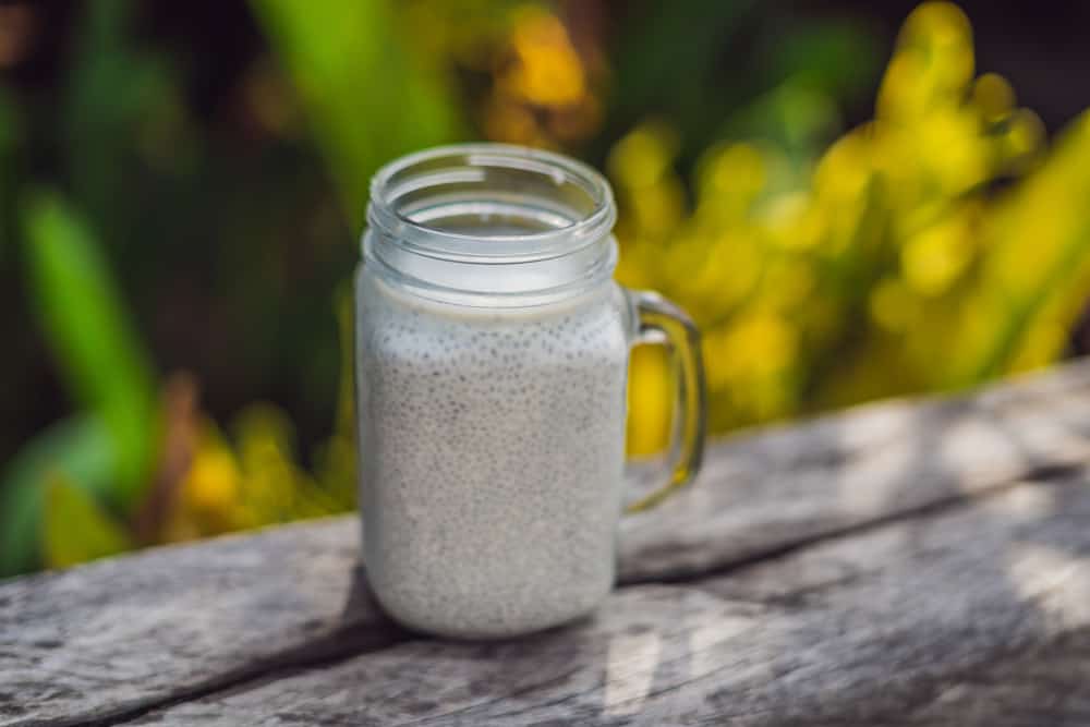 Healthy layered dessert with chia pudding in a mason jar on rustic background.