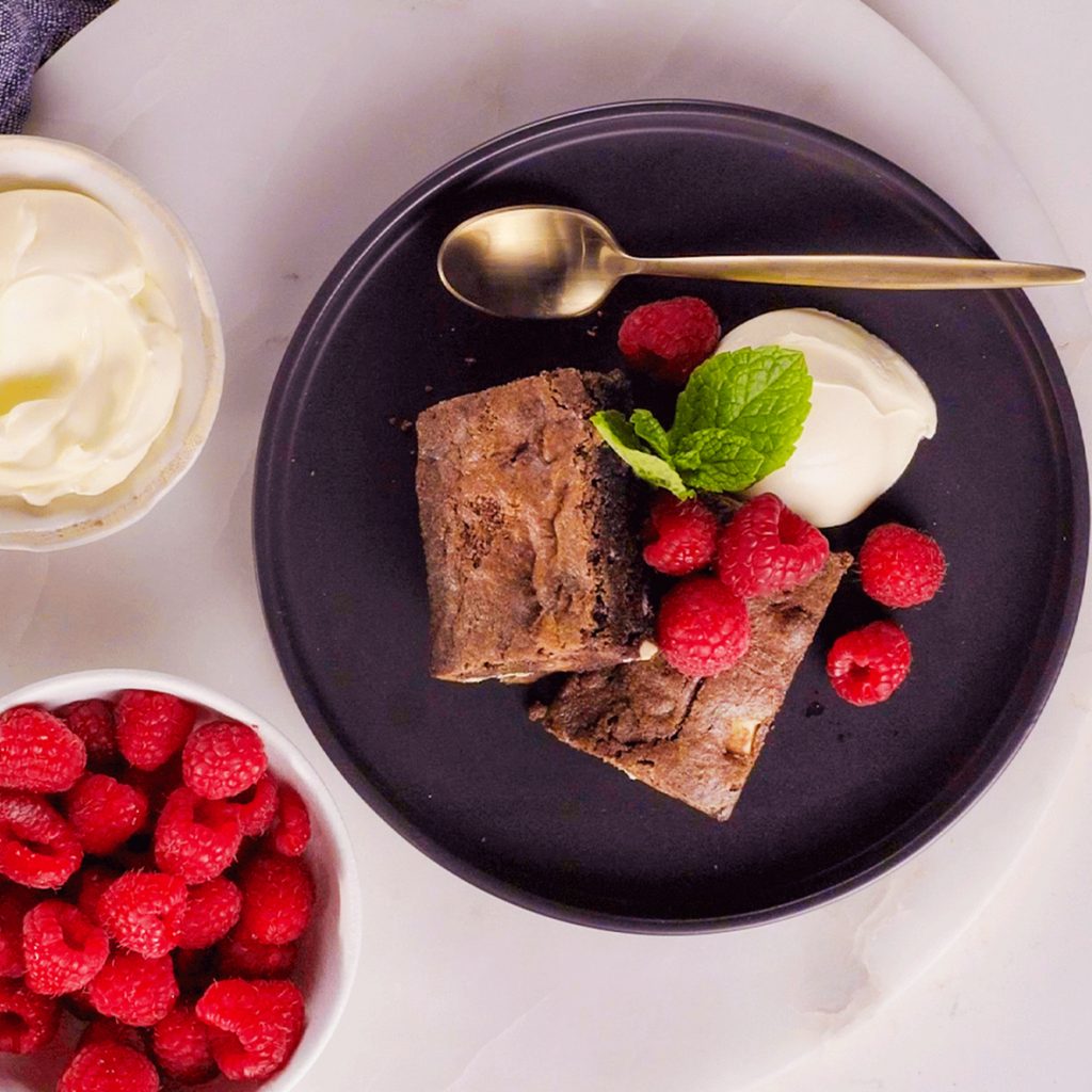 microwave brownie dessert with raspberries and whipped cream on a plate