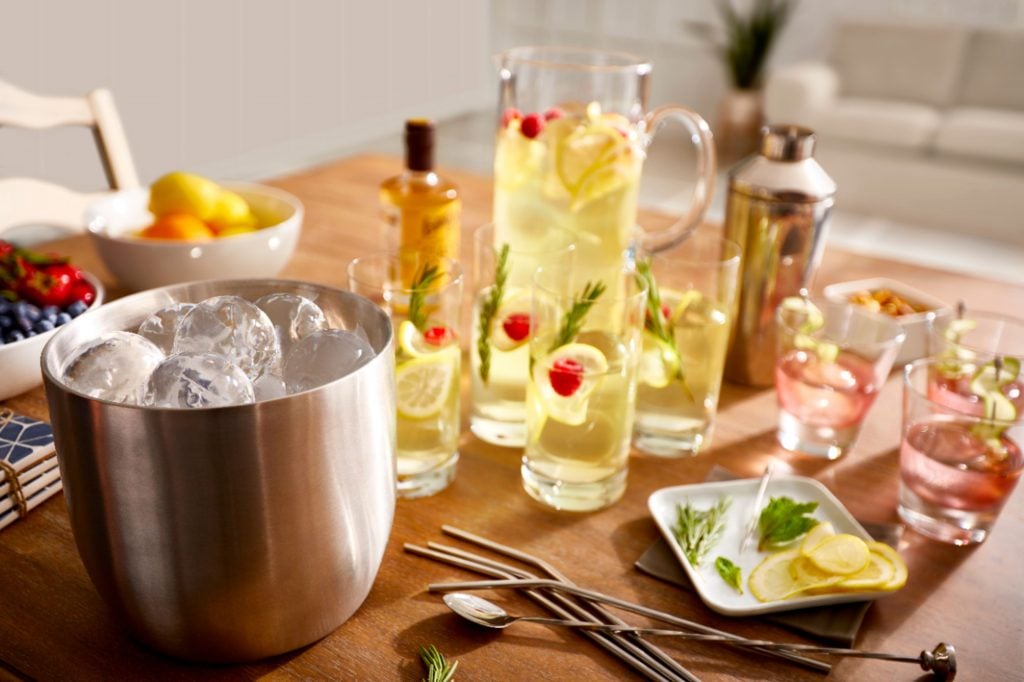 ice bucket with round ice and cocktails on a table