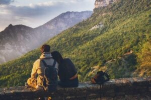 couple sitting on rock wall while hiking in fall