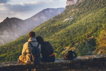 couple sitting on rock wall while hiking in fall