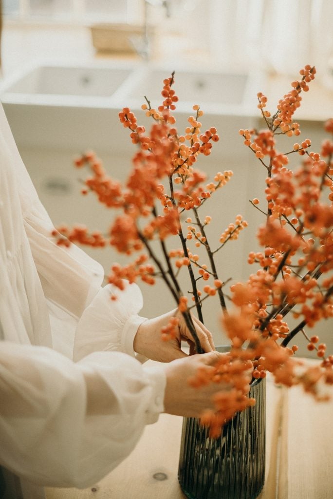 woman arranging a winter vase full of branches and berries