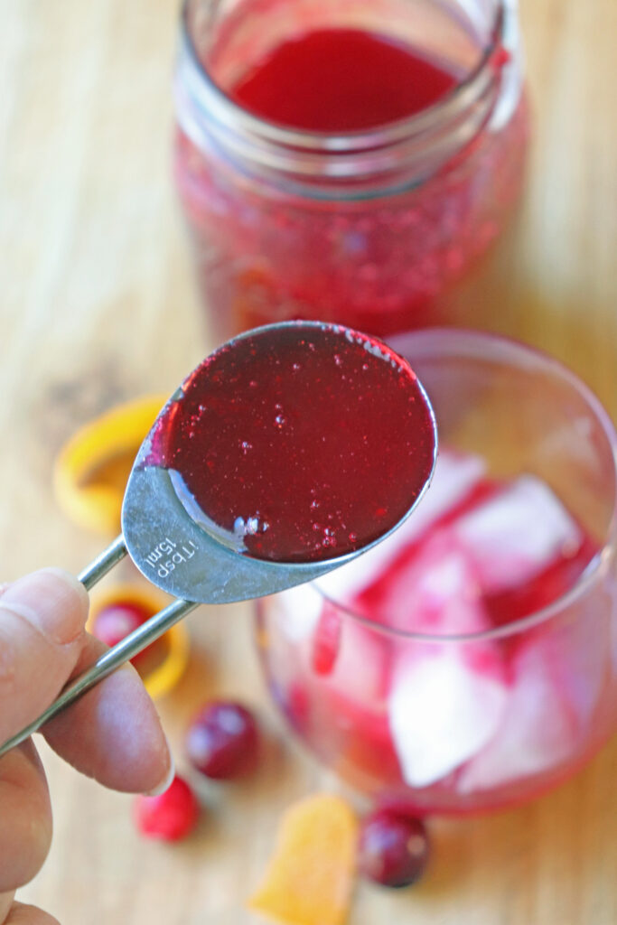 Adding cranberry syrup to glass of homemade soda