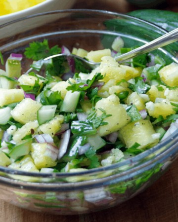 bowl of cucumber salsa with pineapple in glass bowl on cutting board