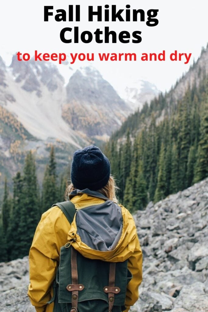 woman hiking on mountain in fall wearing hat and rain jacket with text overlay Fall Hiking Clothes that keep you warm and dry