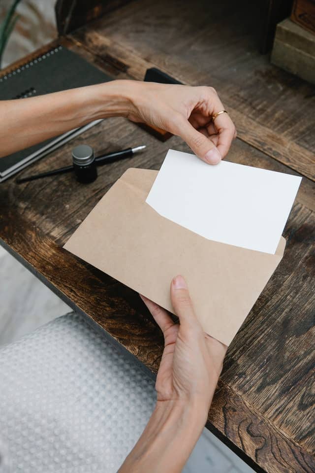 person putting letter to college student in envelope