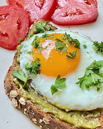 pesto on toast topped with sunnyside up egg and fresh parsley