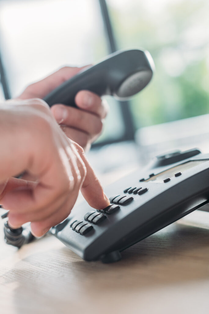 closeup of hand dialing phone on office desk