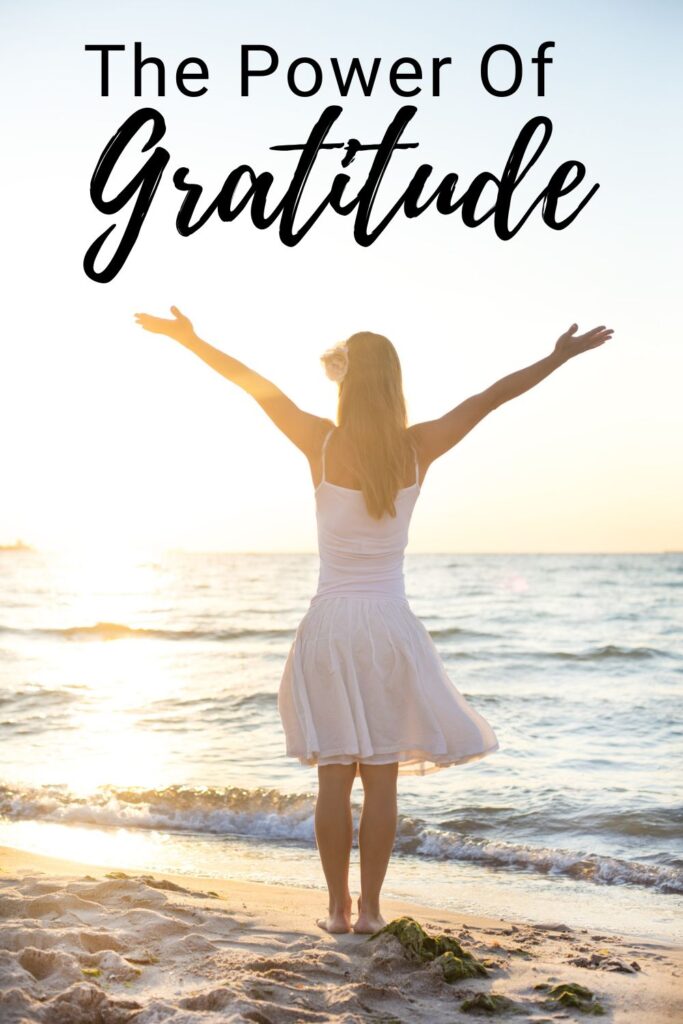 woman with hands outstretched on beach with text overlay 'The Power of Gratitude'