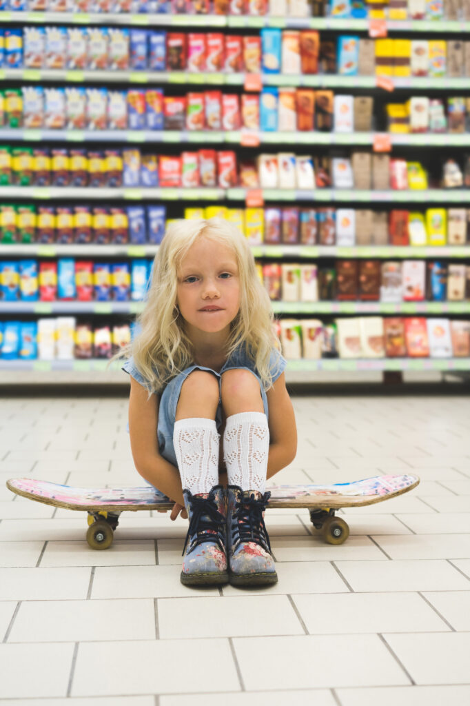 child sitting on floor of grocery isle near packaged foods