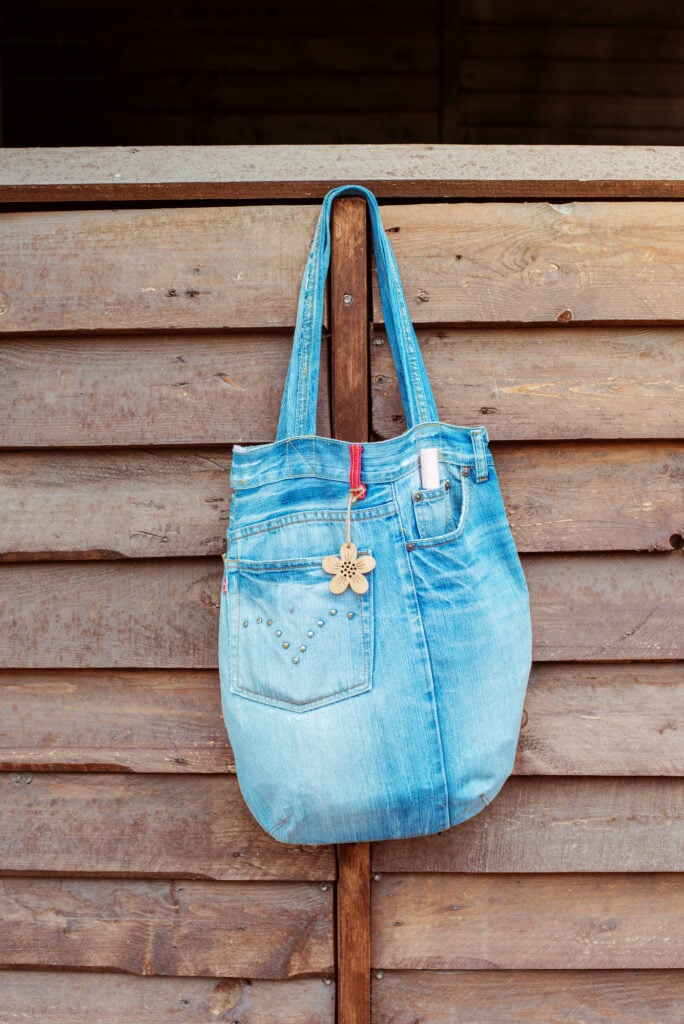 bag made from old jeans hanging on a wood fence