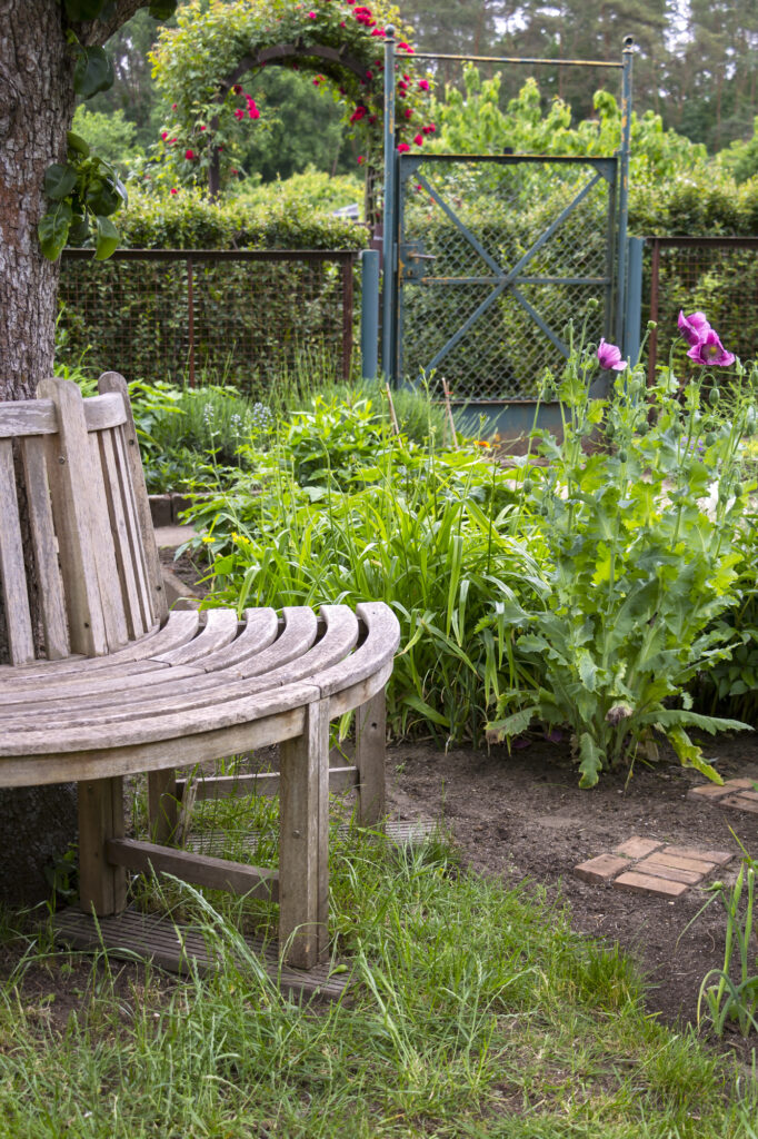 View of a wooden round bench in an allotment garden. There a wonderful place to rest has been created.