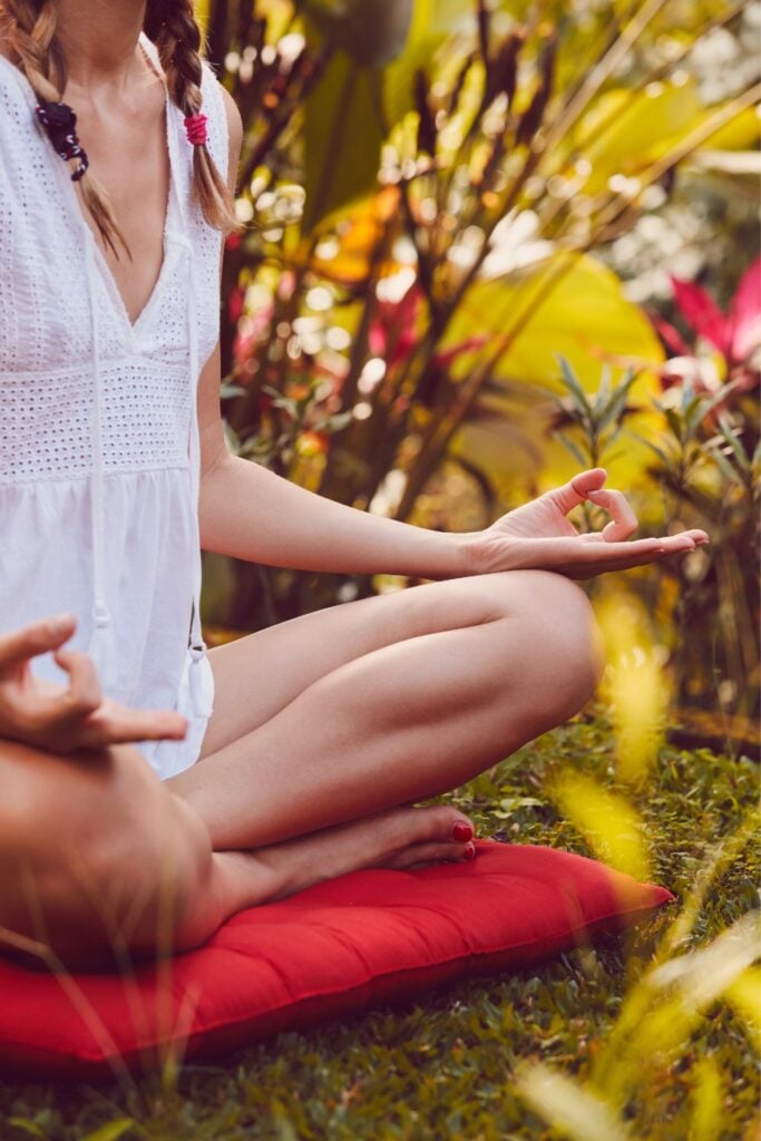 closeup of woman doing seated meditation in meditation garden