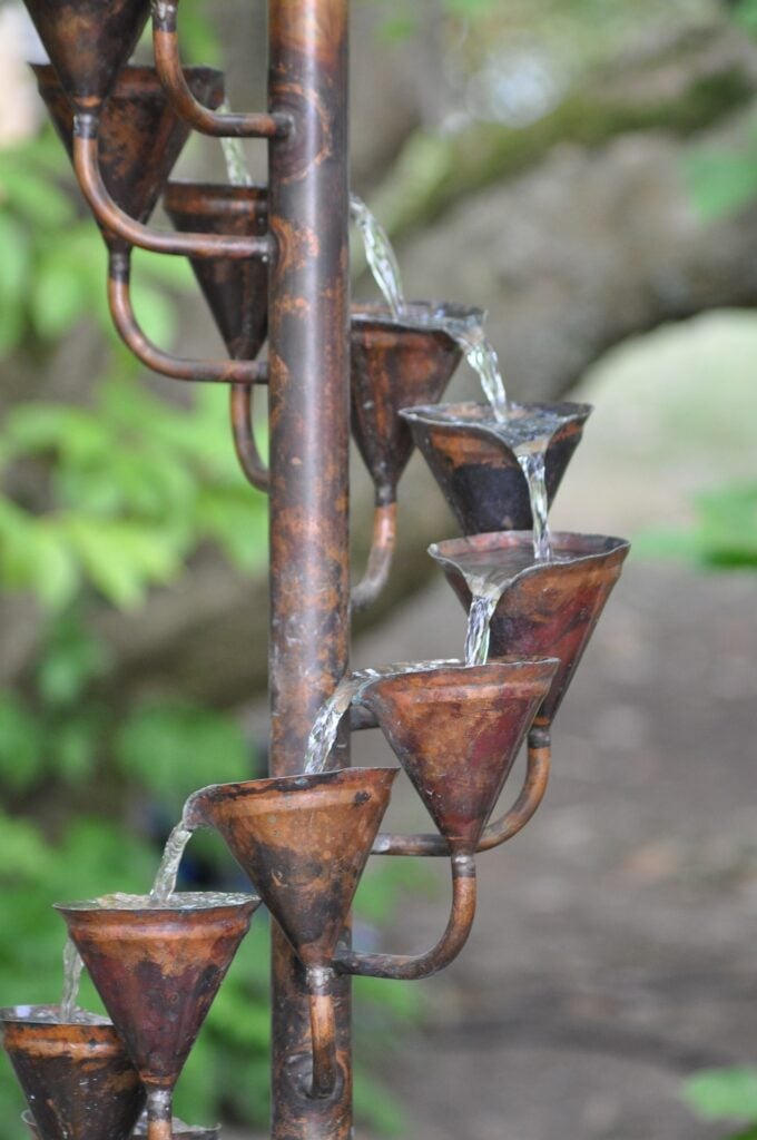 a ladder of copper cups with flowing water passing over them